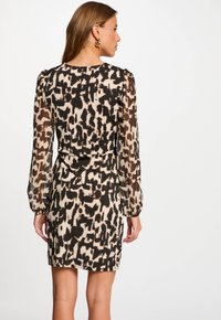 Langemouwen jurk met een luipaardprint in zwart en beige, met doorzichtige mouwen en een getailleerde silhoette, die een gladde stoftextuur toont.
