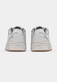 Par lysegrå semskede joggesko med polstrede krager og såler i gummigummi, vist bakfra på en hvit bakgrunn.