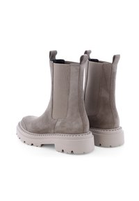 Bottines en suède beige avec une semelle en caoutchouc blanc épais, des panneaux latéraux élastiques et des anses pour un enfilage facile. Fini texturé et bords surélevés.