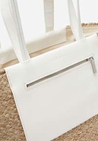 Sac fourre-tout tissé beige avec poche en cuir blanc, fermeture éclair et poignées, présentant la marque "Marc O'Polo" en relief sur une étiquette en cuir.