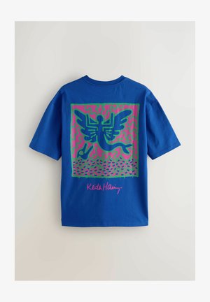 Modra bombažna majica s poudarjeno grafiko v zeleni in roza barvi, ki prikazuje figuro z krili in abstraktnimi vzorci.