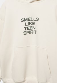 Crèmekleurige hoodie gemaakt van zachte stof met de tekst "SMELLS LIKE TEEN SPIRIT" in donkergroene borduursels. Voorzien van een borstzak.