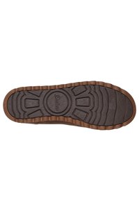 Suela de goma marrón con un patrón de agarre texturizado, que presenta un logo circular y bordes acanalados para una mejor tracción. Diseño de perfil plano y ancho.