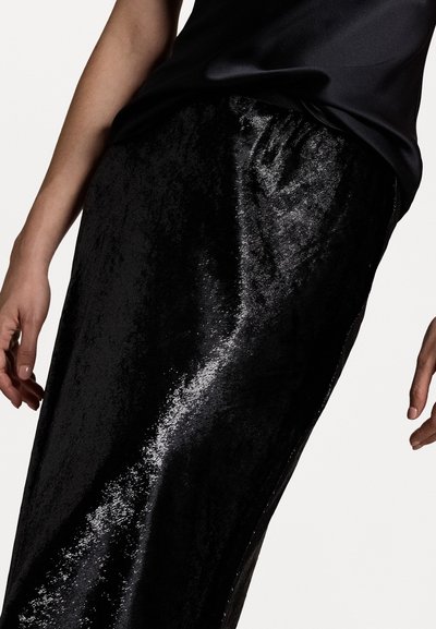Black, shiny skirt made of smooth, reflective fabric, featuring a straight design and an elastic waistband. Accentuated by a dark top.
