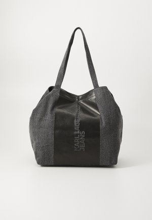 Tummanharmaa silloin rakenne, jossa on teksturoitu kangas ja kiiltävät mustat nahkaosat. Varustettu kahdella tukevalla kahvalla ja kohokuvioidulla logolla sivussa.