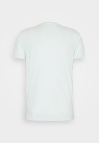 En ljusblå kortärmad t-shirt visas bakifrån med en rund halsringning mot en neutral bakgrund.