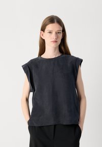 Top corto grigio scuro con maniche corte realizzato in un tessuto leggero e morbido, con scollatura rotonda e vestibilità ampia senza chiusure visibili.