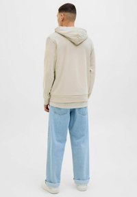 Beige hættetrøje med snoretræk, kængurulomme og ribbede manchetter, parret med lyseblå brede bukser. Enkelt design og komfortabel pasform.