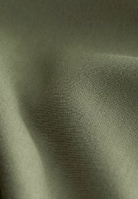 Katoenen stof in een gedempt olijfgroen, met een gladde textuur en subtiele ribbels en een zachte val. Geen zichtbare patronen of accenten.