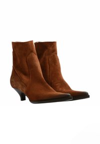 Stivali ankle in suede marrone con punta affilata, forma angolare e tacco nero piccolo. Texture liscia con dettagli di cucitura minimi.