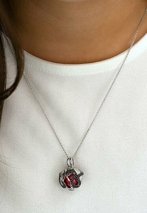Silberne Halskette mit einem runden Anhänger, der einen roten Edelstein in einem Schlangendesign zeigt. Glattes Metall, filigrane Details und glänzende Oberfläche.