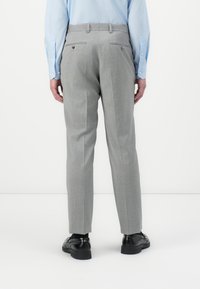 Gray tailored trousers with a textured finish, featuring two back pockets and a slim fit, paired with black shoes and a light blue shirt.