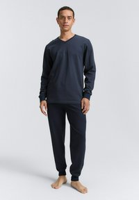 Marineblaue Langarm-Comic-Pyjama-Set mit V-Ausschnitt, gerippter Textur und schmal zulaufenden Hosen, die an den Knöcheln eng anliegen.