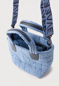 Ανοιχτό μπλε, καπιτονέ τσάντα χειρός με μαξιλαρωτές λαβές, μαύρο φερμουάρ και ρυθμιζόμενο υφασμάτινο λουρί ώμου με μαύρο μοτίβο κειμένου.