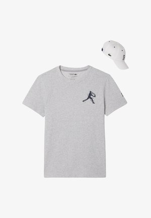 T-shirt di cotone grigio con un logo grafico nero sul petto, accompagnata da un cappellino bianco con un logo sul davanti e sul lato.