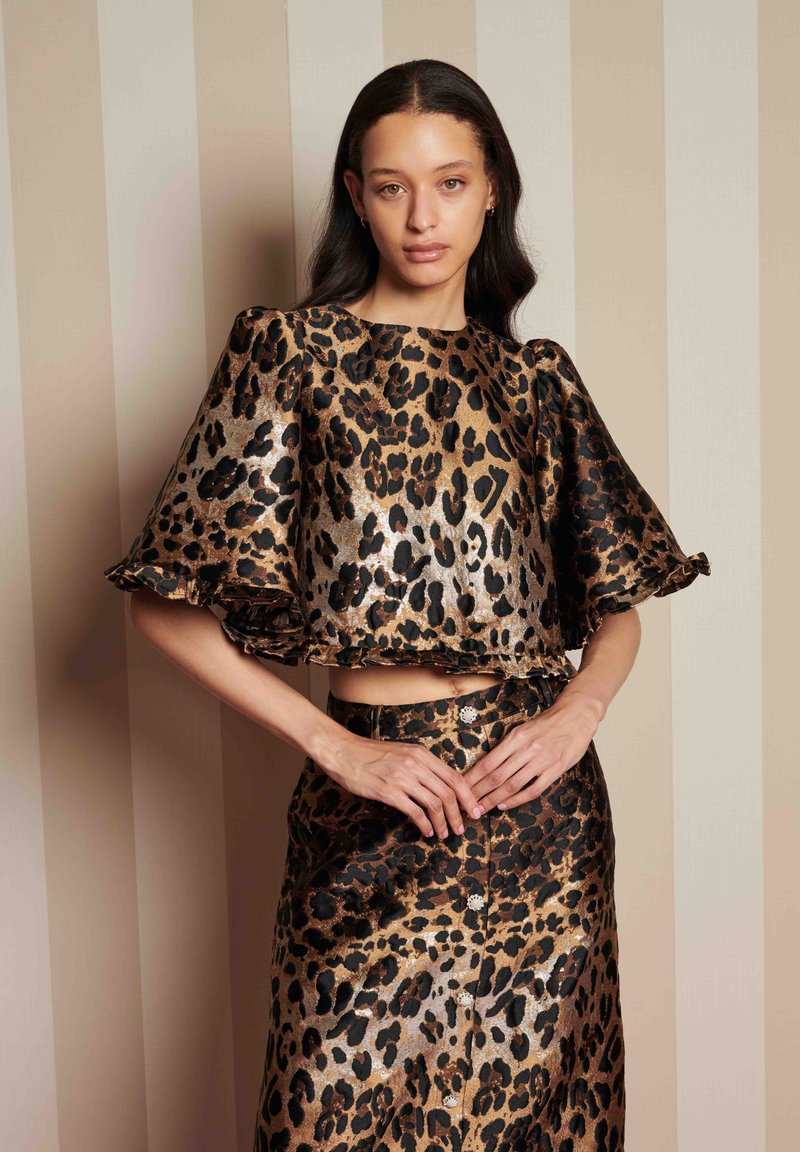 Σύνολο από μπλούζα και φούστα με σχέδιο λεοπάρ σε μεταλλικό ύφασμα, με φουσκωτά μανίκια, cropped σχέδιο και κουμπιά στη φούστα.