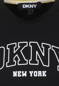 T-shirt noir avec une grande inscription blanche "DKNY NEW YORK". Présente un col rond et une texture en coton lisse.