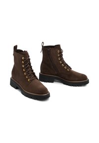 Botas de tobillo de ante marrón con ojales dorados, cordones en la parte delantera, cremallera lateral, puntera redondeada y suela de goma texturizada.