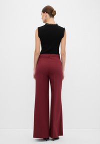 Zwarte geribbelde mouwloze top met ruches, gecombineerd met hoogwaardig, wijde burgundy broek. Soepele textuur en op maat gemaakte stijl.
