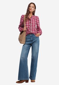 Rød og hvidternet skjorte med knapper, blå brede denimbukser, tan skuldertaske og brune ankelstøvler; glat stof og afslappet pasform.