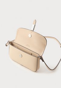 Beżowa skórzana torba na ramię o gładkiej fakturze, z klapką, srebrnym wykończeniem oraz wewnętrzną komorą z subtelnym logo.