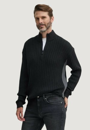 Pullover nero a costine con collo a zip quarti, caratterizzato da un pannello laterale grigio chiaro. Realizzato in maglia testurizzata, maniche lunghe e vestibilità rilassata.