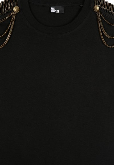 Camiseta de algodón negra con cuello redondo, detalles de acento en cadena en los hombros y una textura suave con un diseño minimalista.