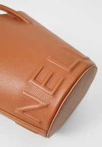 Tan leather handbag with a pebbled texture and embossed design. Features a rounded shape and two short handles.