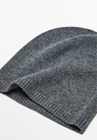 Grau gestrickte Mütze mit weicher Textur und geripptem Rand, die ein glattes Finish und dezente Farbvariationen aufweist.
