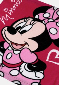 Dečka s motivem Minnie Mouse, vyrobená z živě růžové látky s bílými puntíky a černým obrysem, zobrazuje usmívající se postavu.