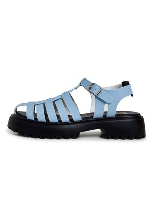 Lilac ribbed crop top, light blue tailored shorts with a scarf tied at the waist, and light blue strappy sandals with chunky black soles.