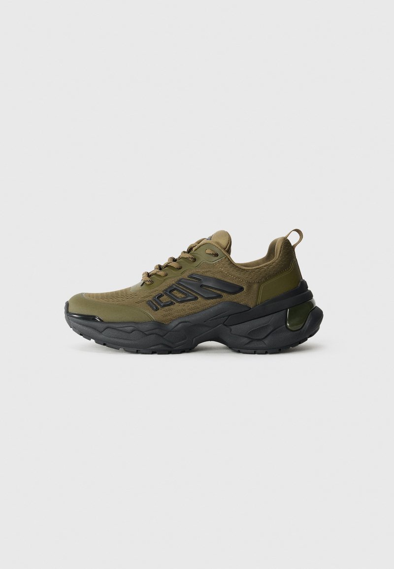 Green athletic shoes with a mesh upper, black accents, thick sole, and textured design. Features laces and a reinforced heel.