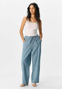 Pantaloni in denim azzurro chiaro a gamba larga con fascia elastica in vita e lacci, dotati di tasche laterali e cuciture a contrasto.