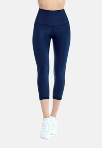 Mörkblå högmidjade leggings med en slät textur, kort längd och smickrande sömmar, kombinerade med vita träningsskor.