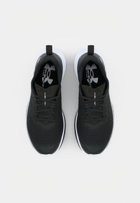 Zapatos deportivos negros con parte superior texturizada, puntera redonda y suelas blancas. Cuentan con cordones y una lengüeta trasera para facilitar su colocación.