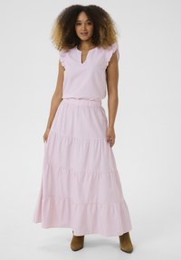 Jupe maxi à volants rayée rose avec taille élastique, associée à un blouse à manches courtes avec volants et un décolleté en trou de serrure.