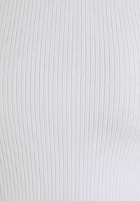 Tessuto bianco a coste con texture verticale. La superficie è liscia con creste distinte e distanziate uniformemente, creando un motivo sottile.