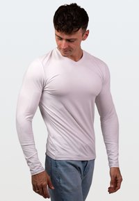 Jasnoróżowa bluzka z długim rękawem o dekolcie w kształcie litery V, dopasowany krój, gładka faktura i szwy boczne dla eleganckiego wyglądu.