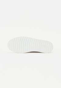 Semelle de sneaker blanche avec un motif nervuré, design plat et un détail de logo prominent au centre. Texture lisse et apparence légère.