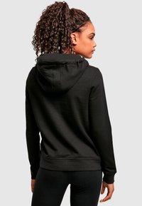 Felpa nera con cappuccio regolabile, texture liscia e polsini a costine. Il design è classico, con una vestibilità comoda e una silhouette semplice.