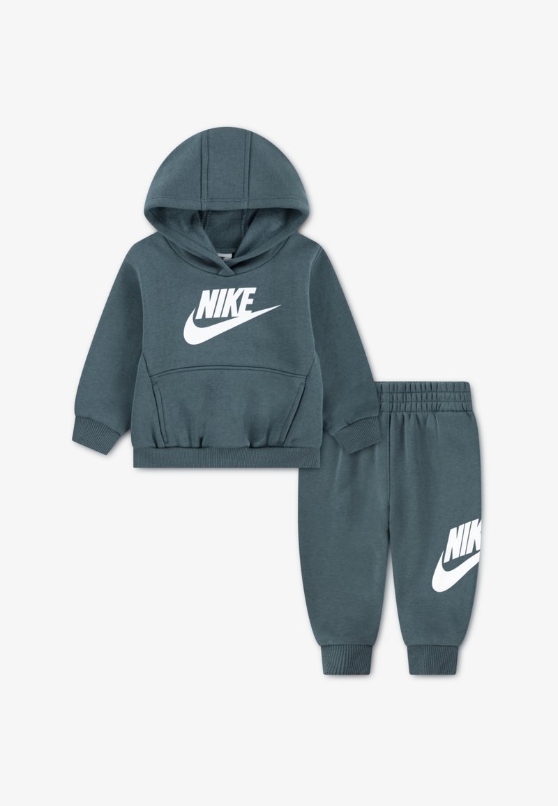 Σετ φούτερ και φόρμας Nike σε τιρκουάζ χρώμα. Το φούτερ διαθέτει μπροστινή τσέπη και λευκό λογότυπο. Οι φόρμες έχουν ελαστική μέση και λογότυπο στο πόδι. Μαλακό υλικό.