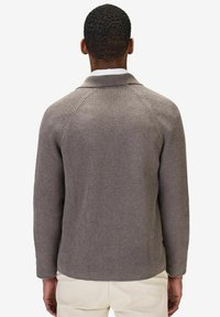 Ribbad stickad kofta i grått med sjalkrans och raglanärmar. Har en avslappnad passform och strukturerad yta.