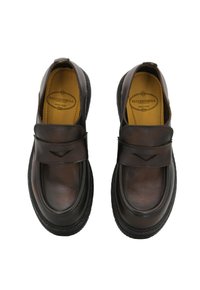 Scarpe in pelle marrone con punta arrotondata, suola piatta e fascia decorativa sopra il piede. Superficie liscia e un leggero lucido.
