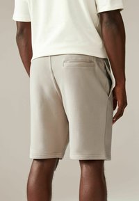 Grå fleece shorts med en baglomme, sideslids og flad talje. Blød tekstur med et rent, enkelt design.