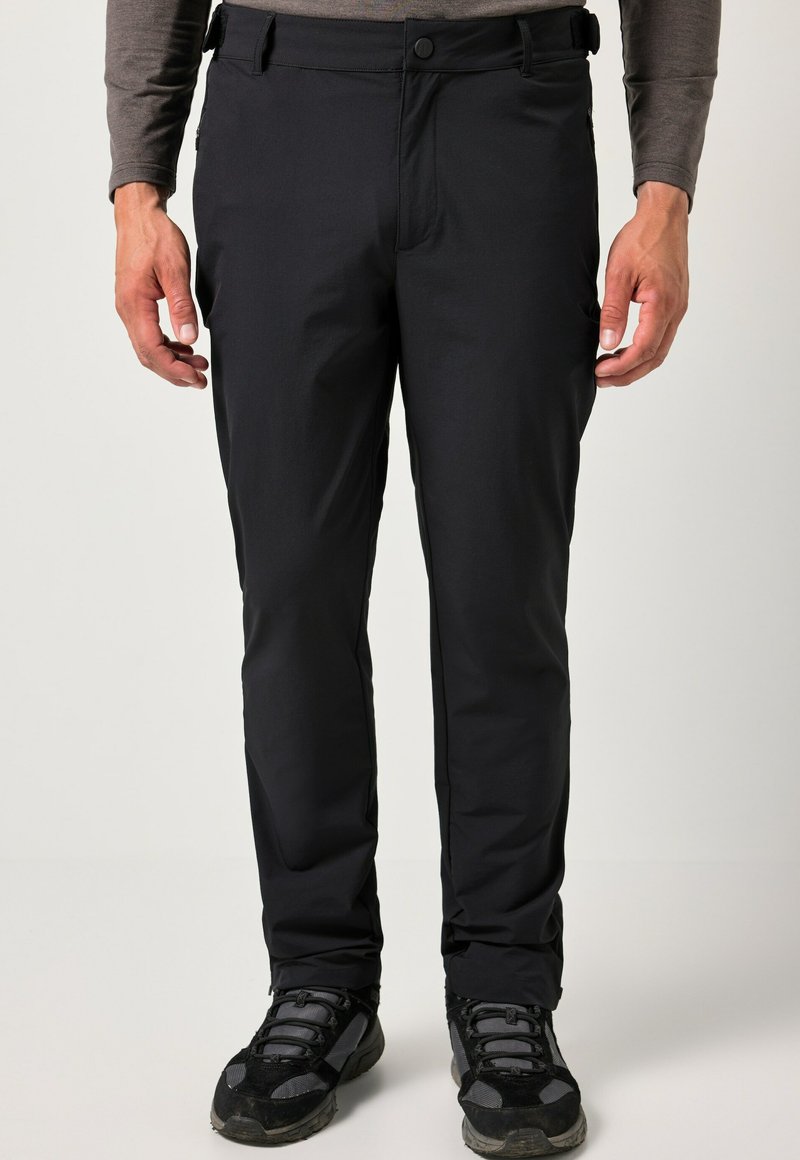 Pantalones exteriores negros con una textura suave y ligera, con cierre de cremallera y botón, usados con zapatos de senderismo negros.