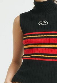 Fekete ujjatlan garbó pulóver bordázott textúrával, piros, sárga és fekete vízszintes csíkokkal, valamint egy kis logóval a középen.