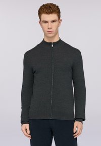 Tmavě šedá zipová mikina s vysokým límcem, žebrovanými manžetami a strukturovanou tkaninou. Má štíhlý střih a minimalistické detaily.