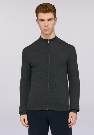 Sudadera de cremallera de color gris oscuro con cuello alto, puños acanalados y tejido texturizado. Presenta un diseño aerodinámico y detalles minimalistas.