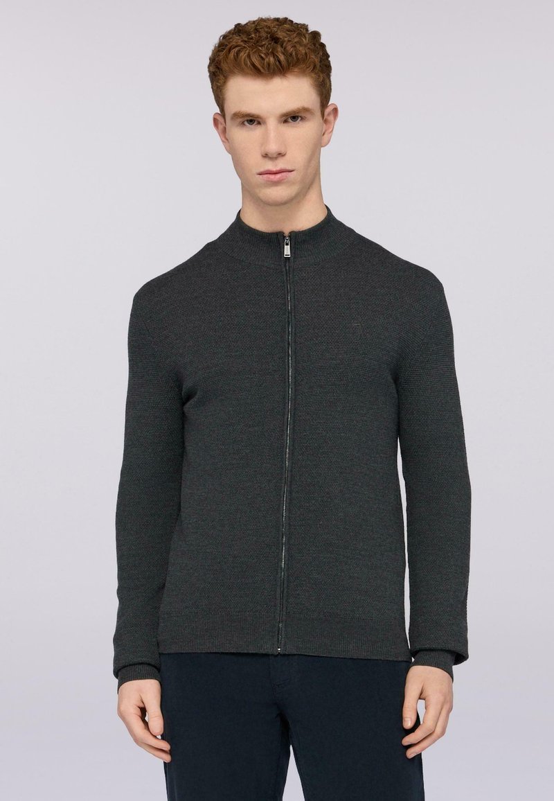 Tmavě šedá zipová mikina s vysokým límcem, žebrovanými manžetami a strukturovanou tkaninou. Má štíhlý střih a minimalistické detaily.