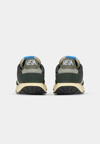 Green and gray sporty sneakers with a blue accent, featuring a textured outsole and a cushioned heel tab. Branding on the back.